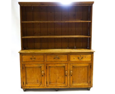 A Victorian pine dresser with two shelf plain plank back under a plain cornice, the base with three drawers and cupboard on t