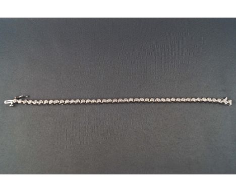 A modern white metal diamond line bracelet. Set with forty two round brilliant cut diamonds measuring approximately 2.20mm di