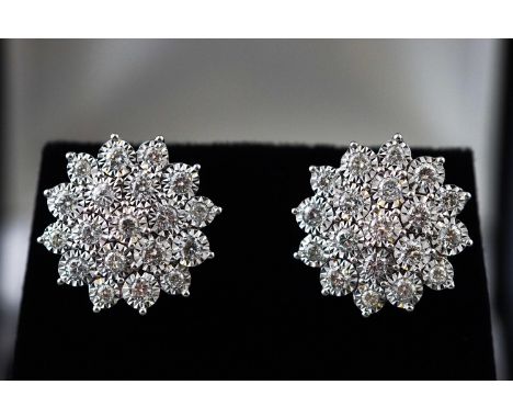 A modern white metal pair of diamond cluster stud earrings. Each set with nineteen round brilliant cut diamonds measuring fro