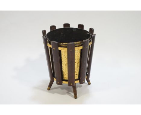 A retro styled brass planter/coal bucket in a hardwood frame, raised on four legs, 39cm high