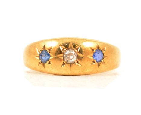 A sapphire and diamond gypsy set ring, one old cut diamond and two sapphires star set in an 18 carat yellow gold tapered band