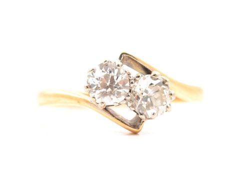 A diamond two stone crossover ring, the old brilliant cut stones claw set in a yellow and white metal mount ring size S, appr