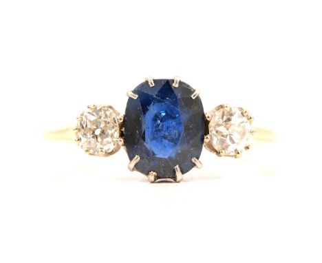 A sapphire and diamond three stone ring, an oval faceted sapphire and two old brilliant cut diamonds claw set in a yellow and