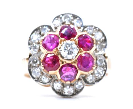 A ruby and diamond reverse cluster floral ring, a central brilliant cut diamond, 3.35mm diameter, claw set and surrounded by 