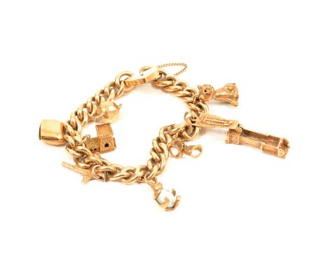 A 9 carat yellow gold charm bracelet and charms, the 9.1mm curb links with padlock fastener and safety chain, hallmarked Lond