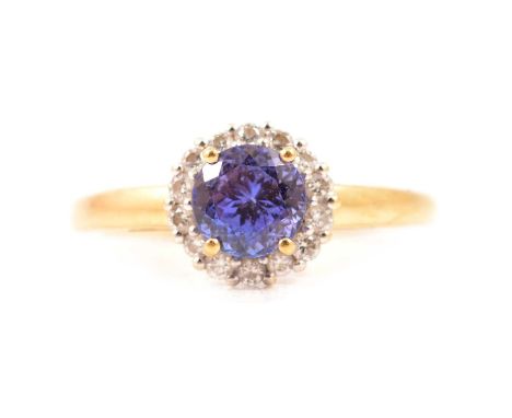 A tanzanite and diamond cluster ring, the round mixed cut tanzanite, 6.1mm x 5.1mm, four claw set and surrounded by fourteen 