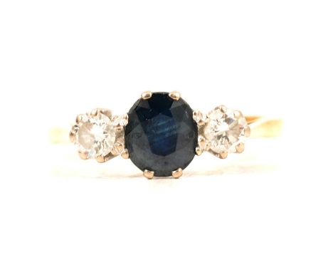 A sapphire and diamond three stone ring, an oval faceted sapphire and two brilliant cut diamonds claw set in a yellow and whi