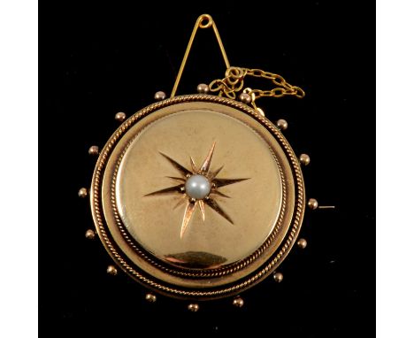 A yellow metal target brooch, 35mm diameter, raised polished centre star set with a pearl, shot work border, locket back, saf