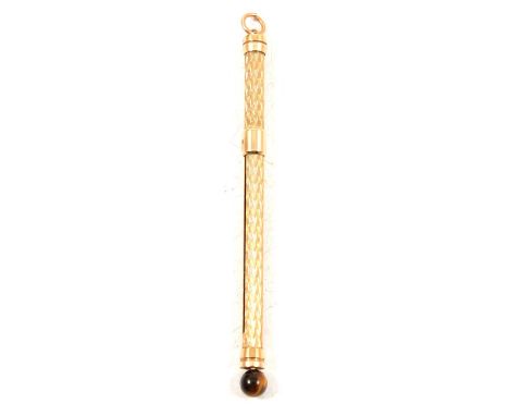 A 9 carat yellow gold swivel stick with tiger's eye bead, engine turned design, Birmingham 1992, 8.5cm, gross weight 7.9g.