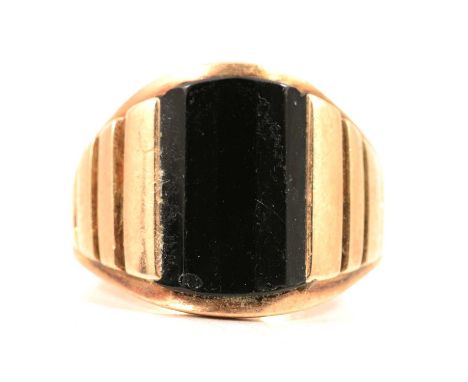 A 9 carat yellow gold onyx signet ring, the faceted onyx panel channel set in a 9 carat yellow gold mount with three panels t