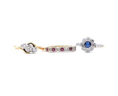 Three gemset rings, diamond, sapphire, ruby, a diamond three stone crossover ring, the brilliant cut diamonds claw set in an 