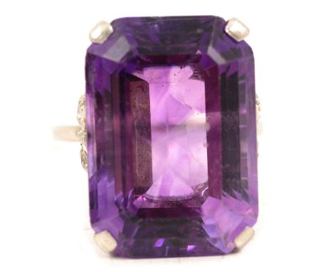 A large amethyst dress ring with diamond shoulders, the emerald cut stone, 21.8x15.5 four claw set in a white metal mount rin