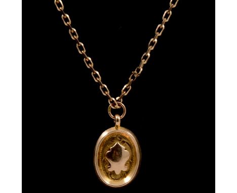 A 9 carat gold pendant and chain, a 9 carat yellow gold oval pendant with plain polished shield to centre of engraved design,