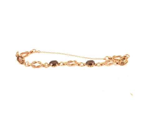 A 9 carat yellow gold bracelet set with four oval mixed cut smoky quartz, joined by reef knot links 7.5mm wide, gross weight 