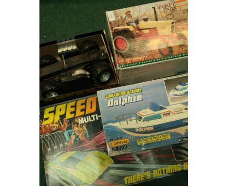 Boxed Dolphin Remote Control Boat, chassis for remote control car, die-cast tractor and a boxed Speed Blurrers racing set (4)