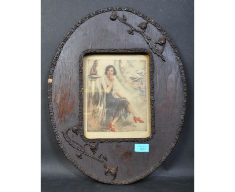 An early 20th century Arts &amp; Crafts oak embellished oval picture frame with inset portrait painting on silk of a seated l