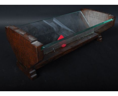 A 1930's Art Deco solid oak and glass book trough. Of angular form with shaped ends having sliding glass panel trough sides