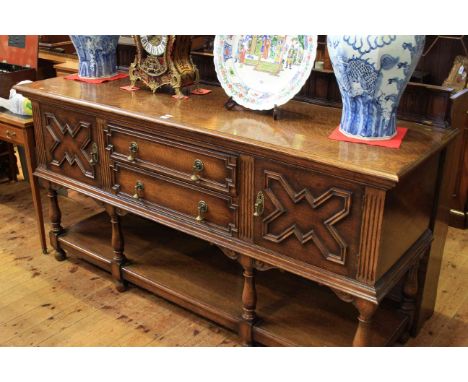 Waring & Gillows, a 1920's oak sideboard, having two central drawers flanked by cupboard doors raised on baluster legs joined