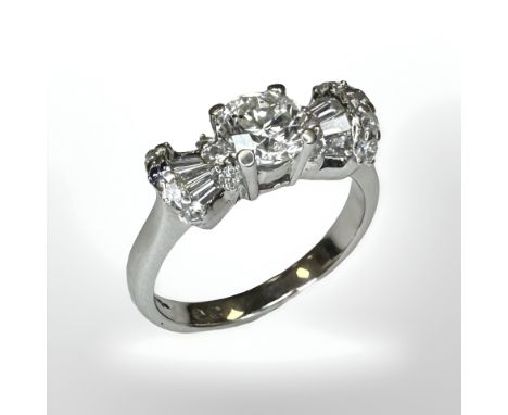 An 18ct white gold diamond ring, the centre brilliant-cut stone 0.82 carat, flanked by baguette and brilliant-cut stones maki