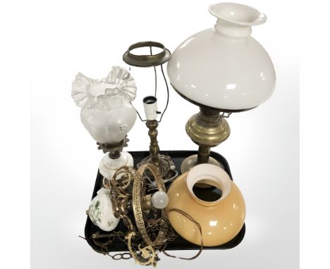 A brass oil lamp with opaque shade, two further lamps (wired) and a pendant light fitting with amber coloured glass shade. 