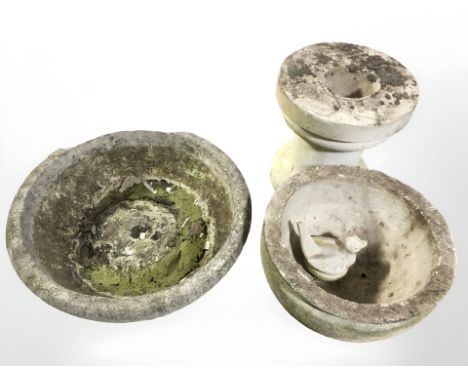 A concrete pedestal circular birdbath, tripod planter and a small figure of a bird.