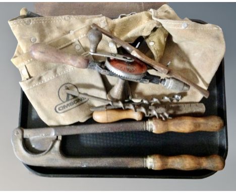 A vintage horse tail docking tool together with a collection of vintage hand tools and a leather tool belt.