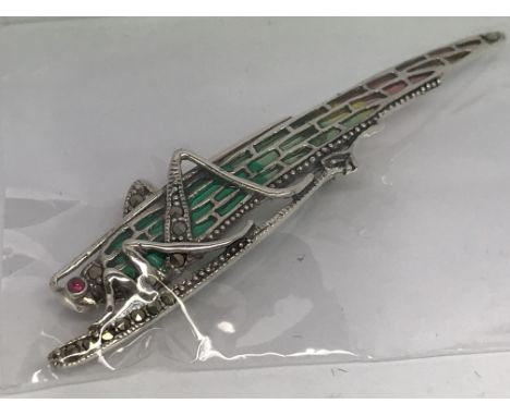 A silver locust brooch set with a pearl in its mouth and marcasites and inlaid with coloured enamel