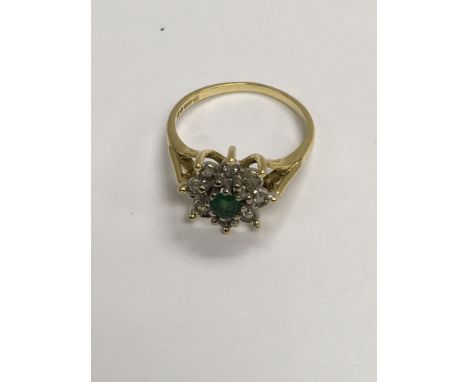 A 18 ct gold ring inset with light emerald surrounded by diamonds.