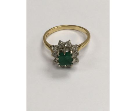 A 18 ct gold ring inset with a square emerald surrounded by diamonds.size N .