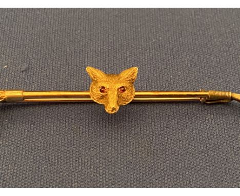 A 9ct gold Fox head and ridding crop bar brooch set with ruby eyes.