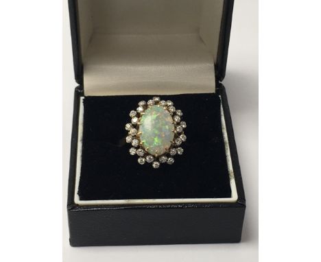 A 18 ct gold ring inset with a central opal surrounded by a cluster of diamonds .size Q