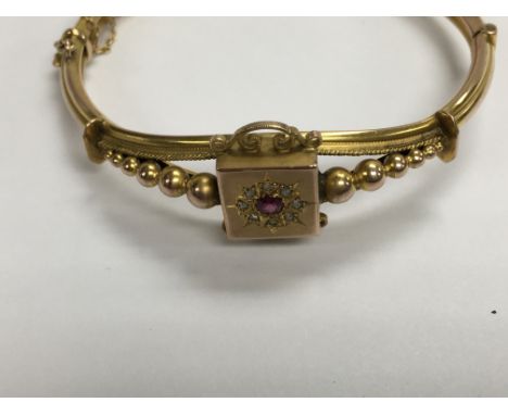 A 9 ct gold Edwardian bangle inset with central ruby surrounded by diamonds .