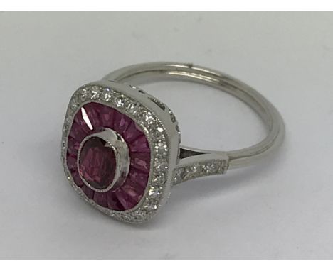 A platinum ring set with central ruby, a halo of calibration-cut rubies and halo of diamonds. Ring size L-M