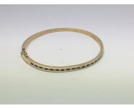 An 18ct gold bangle set with sapphires and diamonds. Approx weight 15g