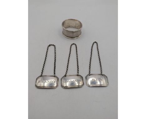 Silver to include three decanter labels 'Brandy', 'Hollands' and 'Rum' together with a napkin ring, total weight 35.8gLocatio