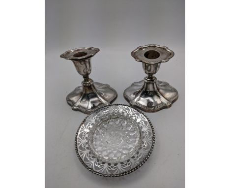 A pair of silver weight candlesticks hallmarked London 1913 along with a silver butter dish hallmarked Birmingham 1935 with a