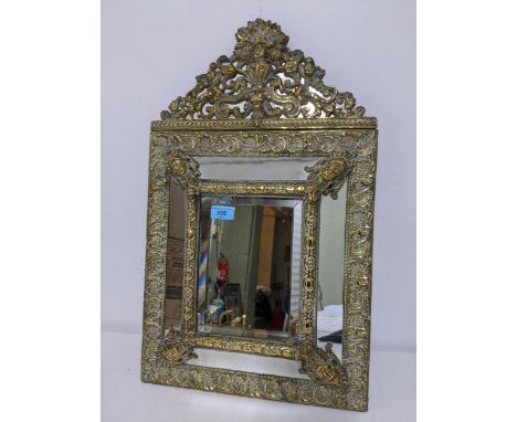A Victorian brass clad wall mirror, ornate urn, floral, flower head and C-scroll decoration, with four classical mask heads j