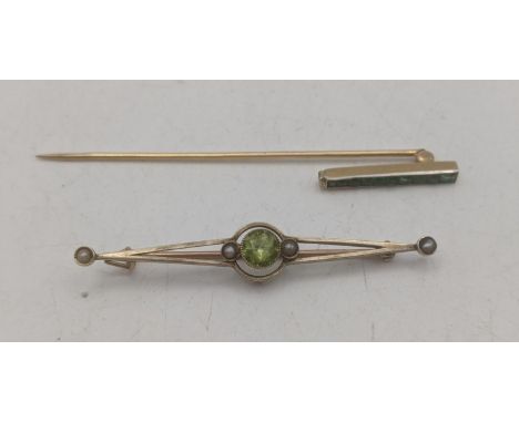 A 9ct yellow gold peridot and seed pearl bar brooch. 2.4g together with a yellow metal stick pin set with a channel set green
