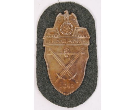 An original WWII Second World War 1942 German DEMJANSK metal plaque / patch. Laid onto fabric. Measures approx; 11cm tall.  N