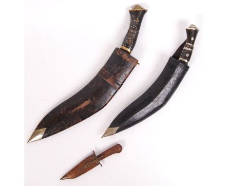 Two early 20th century Kukri knives / daggers, along with a smaller similar knife in a carved wooden scabbard. 