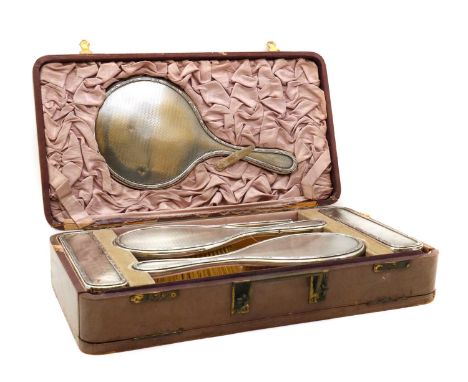 A ladies leather vanity case,London 1922, with four brushes, a looking glass and comb, all with engine-turned silver mounts,c