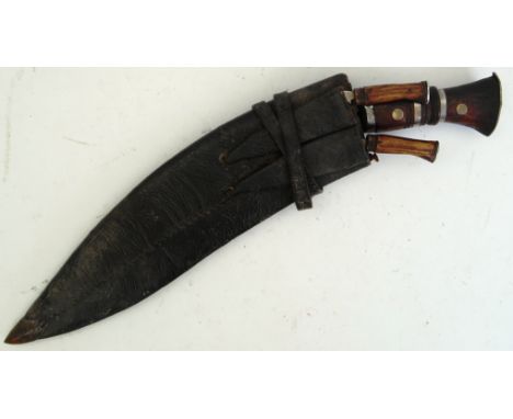 An original 20th century vintage Kukri knife. Large curved blade central knife in leather scabbard, complete with smaller kni