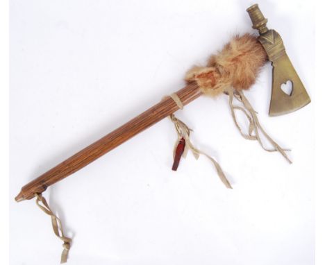 A 20th century Indian Tomahawk axe / pipe. Elongated carved wooden shaft with brass axe head decorated with heart motif. 57cm