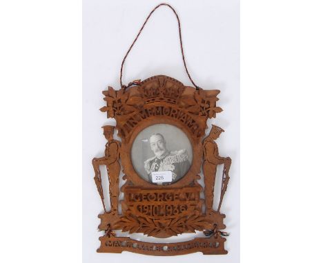 A plaque which is fret carved and topped by the royal crown. It also has a photo of George V to the centre with soldiers eith