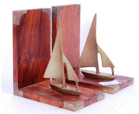 A pair of 20th century treen and brass bookends depicting sailing boats, with brass corners. POSTAGE: Worldwide postage / del
