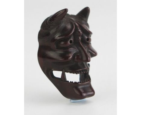 A Japanese carved boxwood netsuke of a noh theatre Hannya mask, signed Doraku, 4.5cm high. Meiji period. 