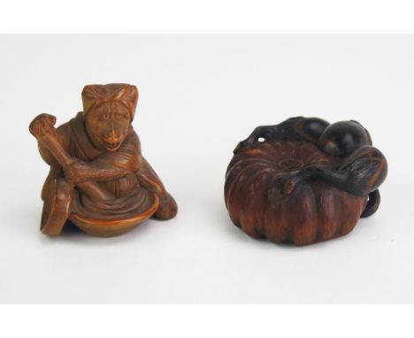 A Japanese carved boxwood netsuke depicting a gourd, signed, 4cm diameter, and another netsuke of a monkey stirring the conte