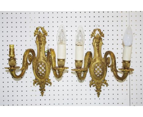A pair of early 20th century gilt metal two light two branch wall sconces, the backs cast with harebells and foliage, grape a