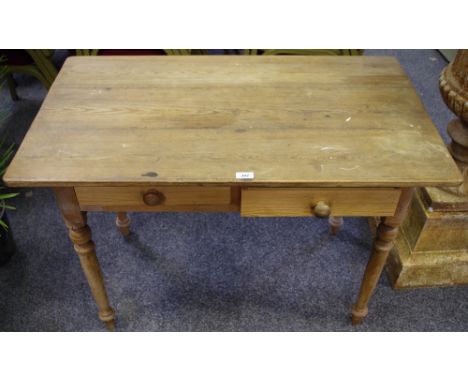 A scrubbed pine kitchen table, plank top, two short drawers to frieze, button handles, turned legs. 70cm high x 102cm long x 