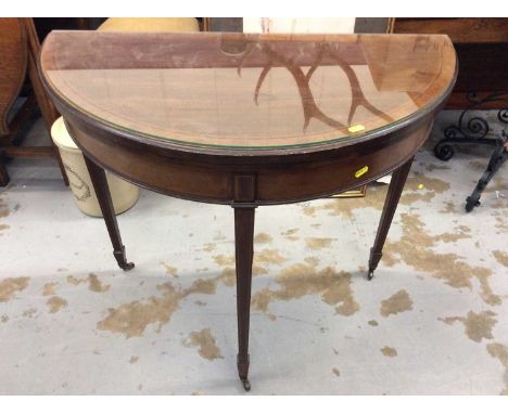 Edwardian Demi lune mahogany card table with inlaid decoration and fold over top on square taper legs with brass casters. 84c